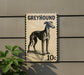 A greyhound dog is depicted on a postage stamp-like sign, mounted on a wall.