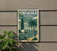 A vintage-style metal sign with a lighthouse and palm tree, mounted on a wall, with a plant to the left.
