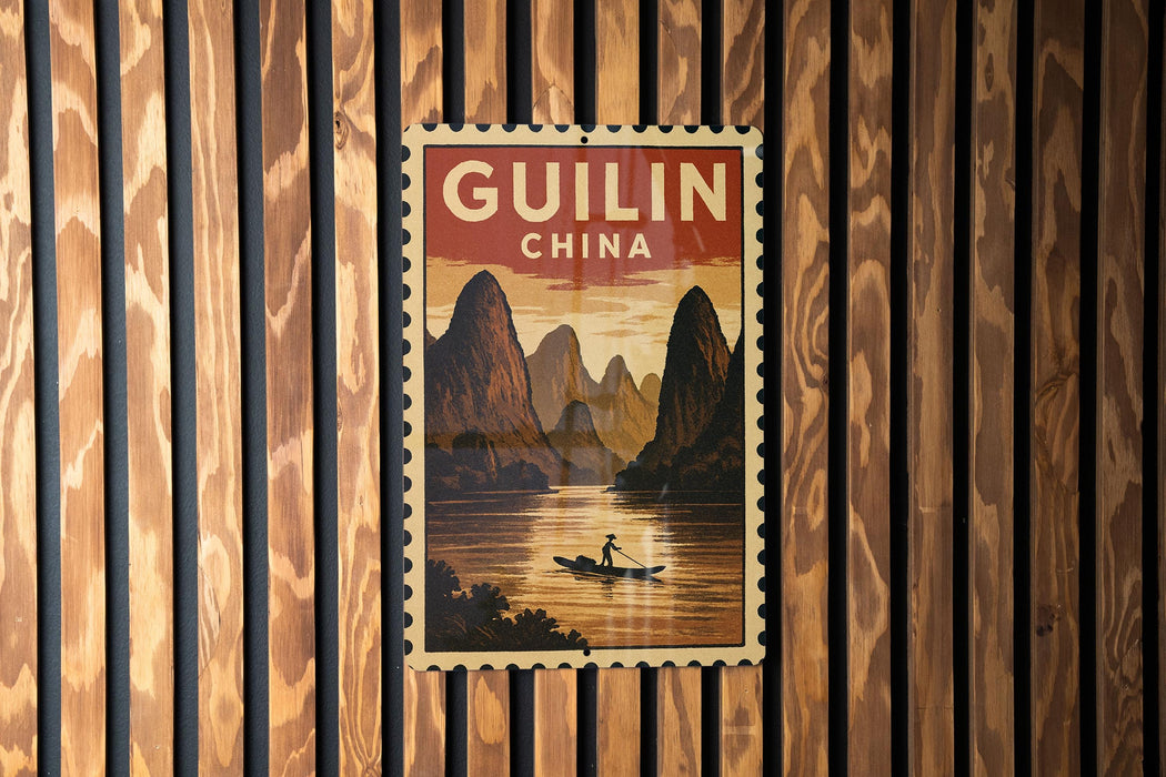 A vintage postage stamp depicting a scenic landscape with mountains, a river, and a person in a boat, hanging on a wooden wall.