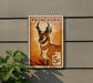 a 5c postage stamp with an illustration of a deer or antelope on it, mounted on a wall.