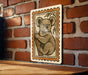 A wooden table with a framed illustration of a koala bear on it, mounted on a brick wall.