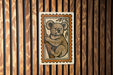 A koala bear illustration is displayed on a wooden wall, with a wooden slat pattern in the background.