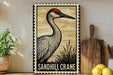 A framed illustration of a sandhill crane is displayed on a shelf, accompanied by a wooden cutting board, a potted plant, and some lemons.