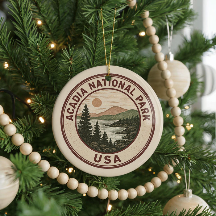 A Christmas tree decorated with ornaments, including a circular ornament with the text "ACADIA NATIONAL PARK USA" and a scenic landscape.