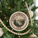 A Christmas tree decorated with ornaments, including a circular ornament with the text "ACADIA NATIONAL PARK USA" and a scenic landscape.