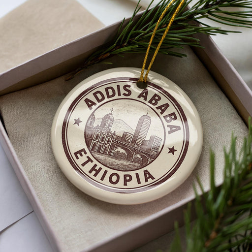 A circular ornament with the text "ADDIS ABBA" and "ETHIOPIA" printed on it, placed inside a box with pine branches.