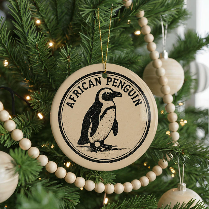 A round ornament on a Christmas tree featuring an illustration of an African penguin.