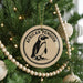 A round ornament on a Christmas tree featuring an illustration of an African penguin.