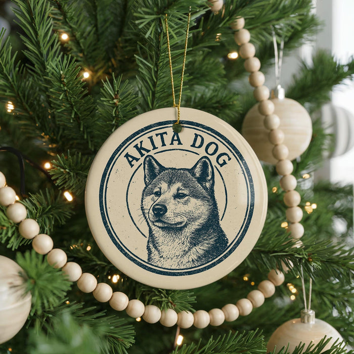 A Christmas tree decorated with ornaments, including a circular ornament with a picture of a dog and the text "AKITA DOG" on it.