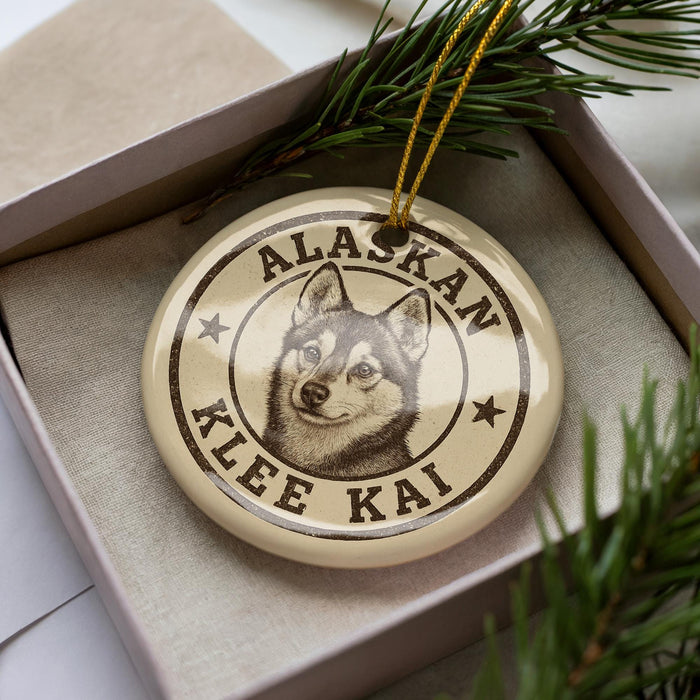 A circular ornament with a dog image and text, placed in a box with pine branches.