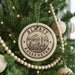 A circular ornament on a Christmas tree, featuring the text "ALMATY KAZAKHSTAN" and an illustration of a cityscape with mountains in the background.