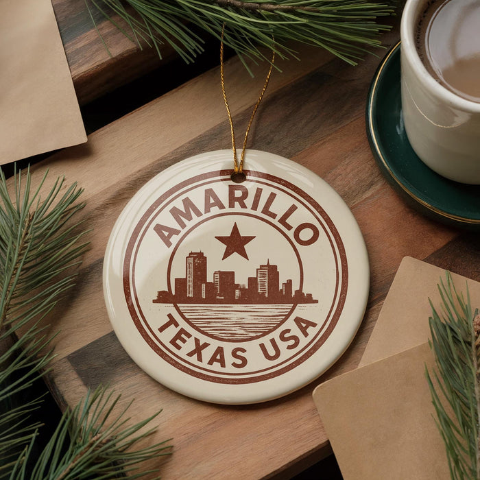 A circular ornament with the text "AMARILLO TEXAS USA" and a graphic of a city skyline is displayed on a wooden surface, surrounded by pine branches and a cup of coffee.