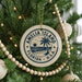 A Christmas tree decorated with ornaments, including a circular ornament with the text "AMELIA ISLAND FLORIDA U.S.A."