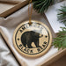 A circular ornament with a black bear image and the text "AMERICAN BLACK BEAR" is displayed in a box with pine branches.