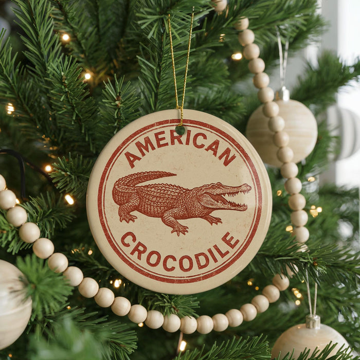 A Christmas tree decorated with ornaments, including a circular ornament with a red and white design featuring a crocodile and the text "AMERICAN CROCODILE".