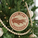 A Christmas tree decorated with ornaments, including a circular ornament with a red and white design featuring a crocodile and the text "AMERICAN CROCODILE".