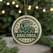A round ornament with a snake design and the word "ANACONDA" printed on it, hanging from a string.