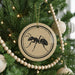 A Christmas tree decorated with ornaments, including a circular ornament with a black ant design.