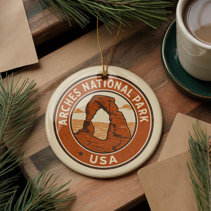 A circular ornament with the text "ARCHES NATIONAL PARK USA" and an illustration of a rock formation, hanging on a wooden surface.