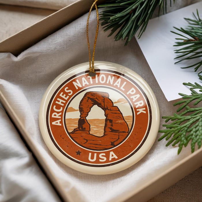 A circular ornament with the text "ARCHES NATIONAL PARK USA" and an illustration of a rock formation, hanging from a string.