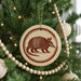 A Christmas tree decorated with ornaments, including a circular ornament featuring an armadillo design.