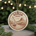 A circular ornament with a sailboat and a castle in the background, surrounded by Christmas lights.
