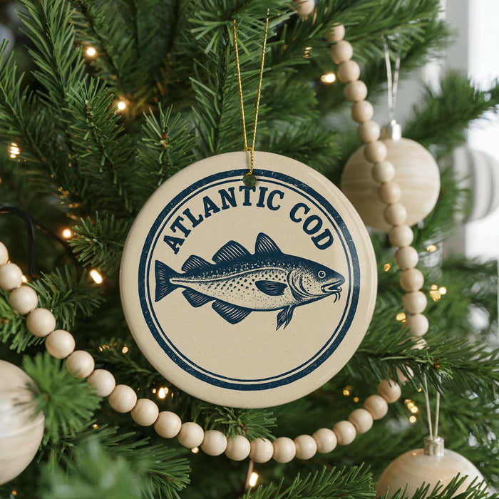 A Christmas tree decorated with ornaments, including a circular ornament with a fish design and the text "ATLANTIC COD" printed on it.