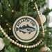 A Christmas tree decorated with ornaments, including a circular ornament with a fish design and the text "ATLANTIC COD" printed on it.