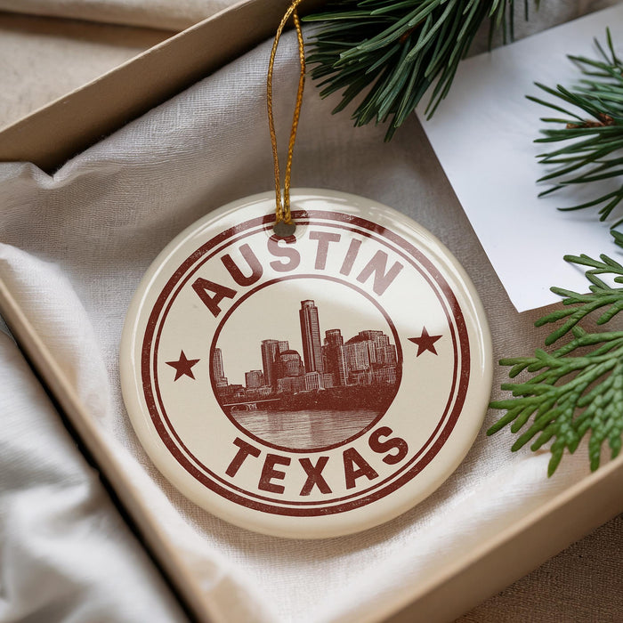 A circular ornament with the text "AUSTIN TEXAS" printed on it, surrounded by a star symbol, is displayed in a box with pine branches.