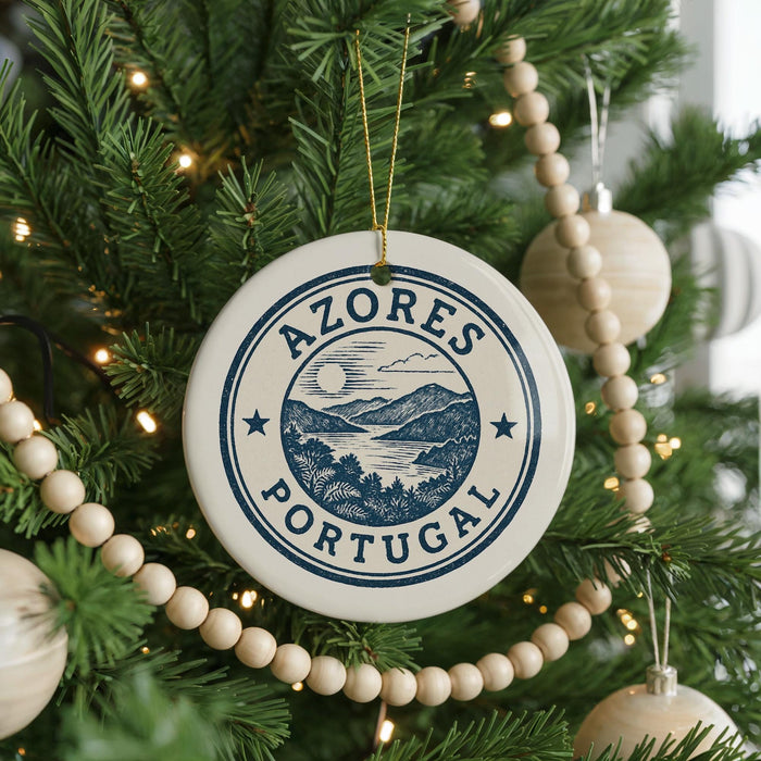 A Christmas tree decorated with ornaments, including a circular ornament with the text "AZORES PORTUGAL" and a landscape scene.