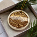 A circular ornament with the text "BADLANDS NATIONAL PARK USA" printed on it, surrounded by pine branches.