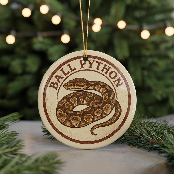 A round ornament with the text "BALL PYTHON" and an illustration of a snake is displayed in front of a Christmas tree with twinkling lights.