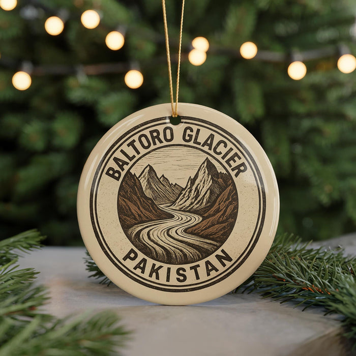 A circular ornament with a mountain landscape and a winding river, surrounded by Christmas lights.