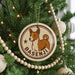 A Christmas tree decorated with ornaments, including a circular ornament with a brown and white dog image and the name "Basenji" written on it.