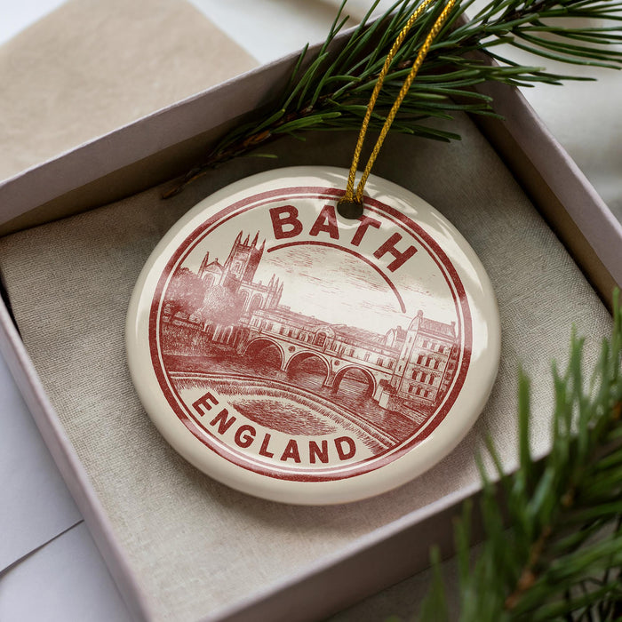 A circular ornament with the text "BATH ENGLAND" printed on it, surrounded by pine branches.