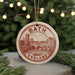 A circular ornament with the text "BATH ENGLAND" and an illustration of a cityscape, hanging from a string.