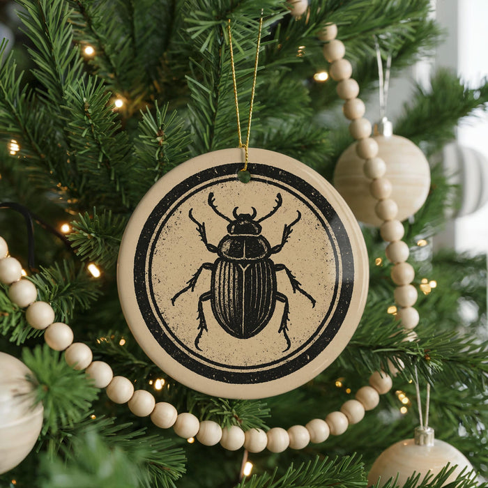 A Christmas tree decorated with ornaments, including a circular ornament featuring a black and white illustration of a beetle.