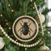 A Christmas tree decorated with ornaments, including a circular ornament featuring a black and white illustration of a beetle.