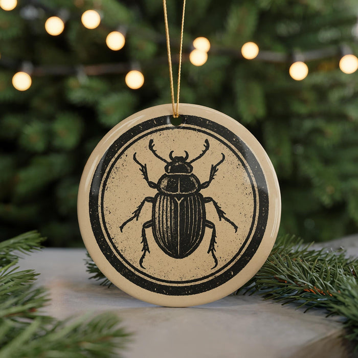 A circular ornament featuring a detailed illustration of a beetle is displayed against a blurred background of greenery and twinkling lights.