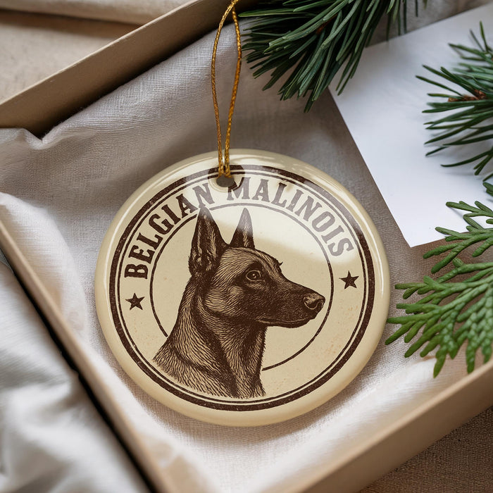 A round ornament featuring a dog's head and the text "Belgian Malinois" is displayed in a box with pine branches.
