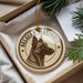 A round ornament featuring a dog's head and the text "Belgian Malinois" is displayed in a box with pine branches.
