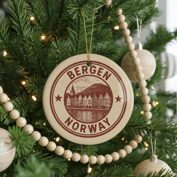 A Christmas tree decorated with ornaments, including a circular ornament with the text "BERGEN NORWAY" and a scenic illustration of a town.