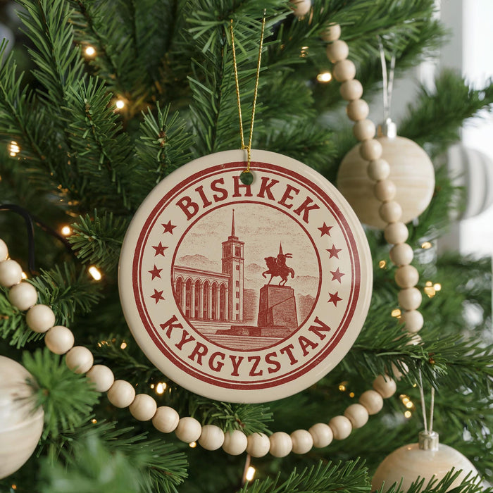 A Christmas tree decorated with ornaments, including a circular ornament with the text "BISHKEK Kyrgyzstan" and a picture of a building.