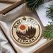 A circular ornament with the text "Black Forest Germany" and an illustration of a forest scene with a red sun in the sky.