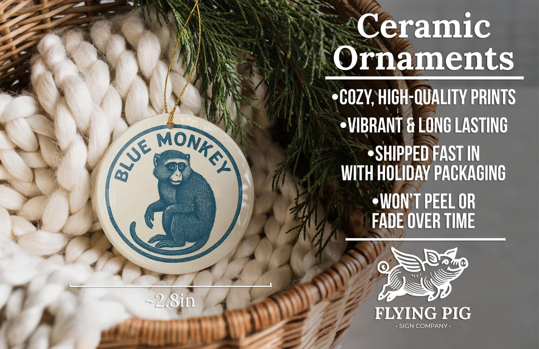 a ceramic ornament with a blue monkey design, hanging from a wicker basket. The ornament is described as a "Ceramic Ornaments" and is described as "Cozy, High-quality Prints" and "Vibrant & Long Lasting". It is also noted that the ornament is "Shipped Fast in with Holiday Packaging" and " Won't Peel or Fade Over Time". The image is a single, uncluttered scene with the focus on the ceramic ornament and the wicker basket.