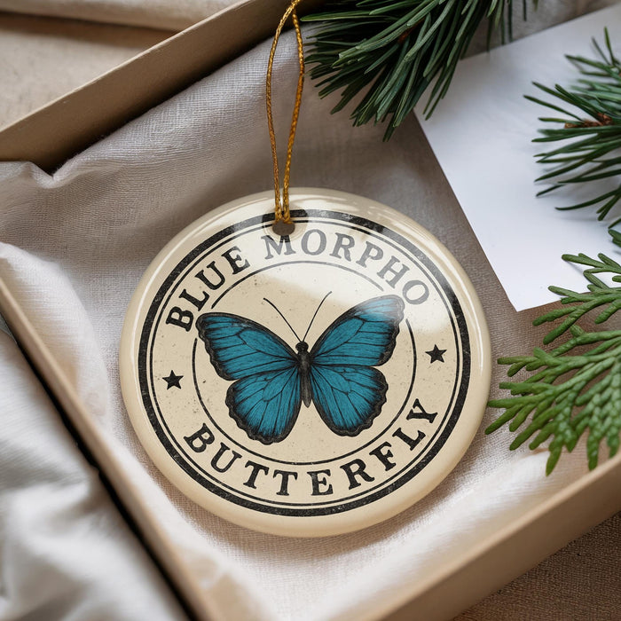 A decorative ornament featuring a blue butterfly, with the text "BLUE MORPHO BUTTERFLY" printed on it, is displayed in a box with pine branches.