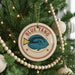 A Christmas tree decorated with ornaments, including a circular ornament with a blue fish and the text "BLUE TANG" on it.