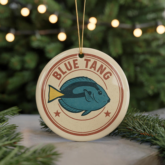 A round ornament with a blue fish design and the text "BLUE TANG" on it, hanging from a string.