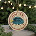 A round ornament with a blue fish design and the text "BLUE TANG" on it, hanging from a string.
