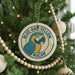 A Christmas tree decorated with ornaments, including a circular ornament with a parrot design and the text "BLUE-AND-YELLOW MACAW" on it.
